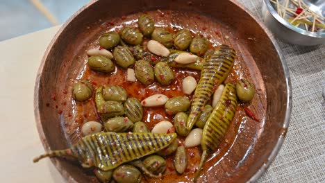 Primer-Plano-De-Aceitunas-Verdes-A-La-Parrilla,-Ajo-Y-Encurtidos-De-Chile-Verde-Se-Muestran-Durante-La-Exposición-De-Comida-Del-Golfo