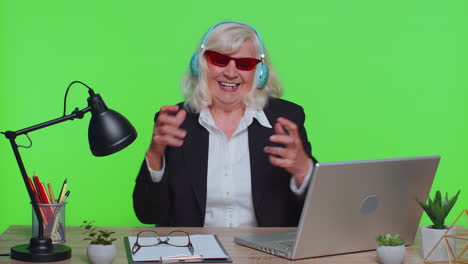 Senior-business-woman-listening-music-on-headphones,-dancing-disco-fooling-around,-celebrating-win