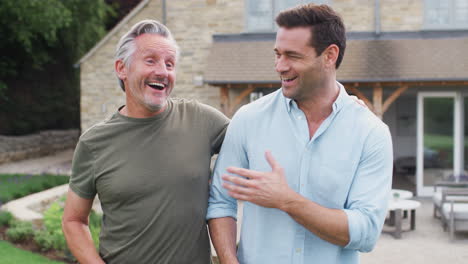 Senior-Father-With-Adult-Son-Walking-And-Talking-In-Garden-Together