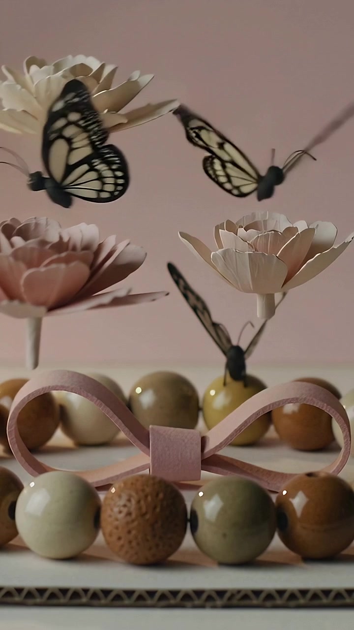 Vertical video: Cam shifting focus, butterflies flitting on cardboard base showing beads, pink bow