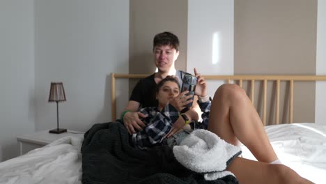 pareja relajándose en la cama con un teléfono inteligente