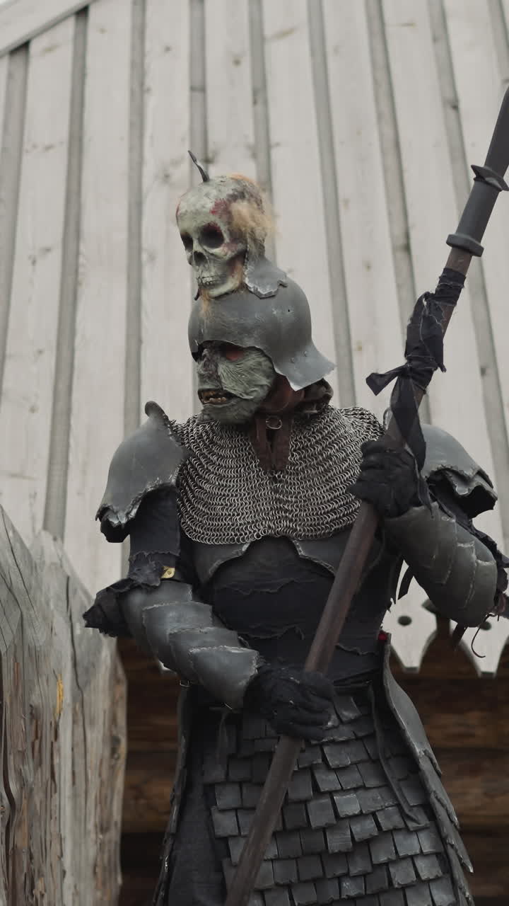 caballero con armadura pesada y casco patrulla el perímetro del asentamiento. guerrero con lanza examina el área fuera de la aldea mirando a la distancia más allá de la valla