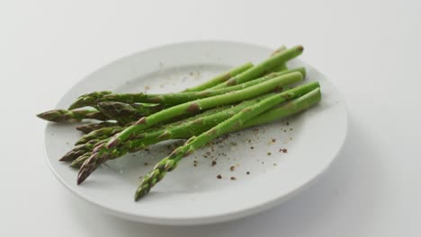 Video-of-fresh-asparagus-stalks-on-white-plate-over-white-background