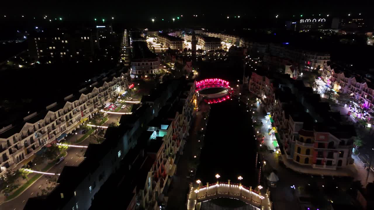 This close aerial footage offers a detailed nighttime view of Grand World, where the surrounding trees are spectacularly decorated with a multitude of colorful lights, a festive and magical ambiance.