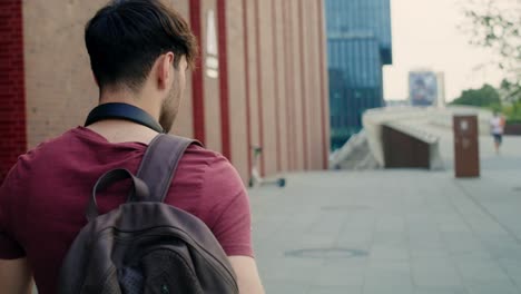 Back-view-of-caucasian-student-walking-through-university-campus