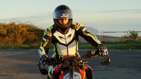 motorcyclist in gear on sport bike on scenic roadside during sunset with a distant view
