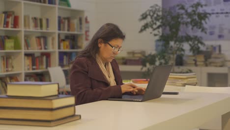 Seitenansicht-Einer-Reifen-Dame,-Die-Formals-Trägt-Und-Auf-Ihrem-Laptop-Im-Büro-Sitzt