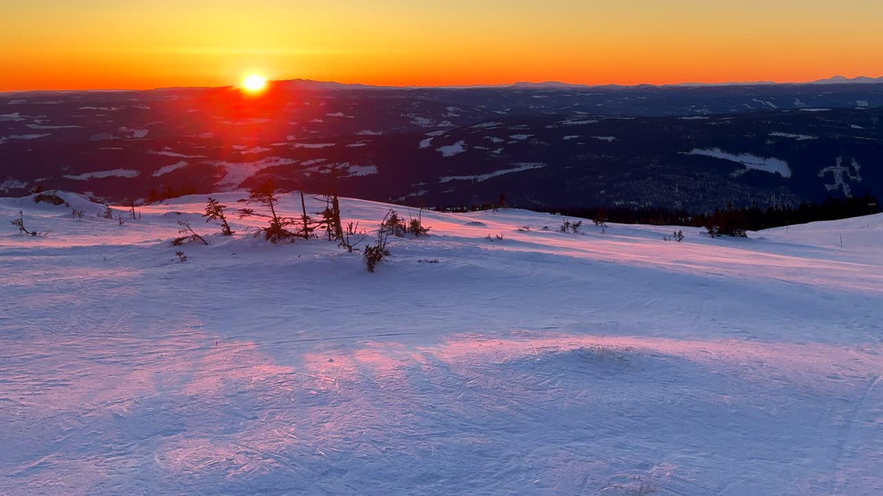 Olympic torch man on top of Øyer mountain Lillehammer Hafjell Alpine resort Norway Norge chairlift groomed trail ski runs golden hour vibrant sunset winter terrain landscape breeze frigid pan left