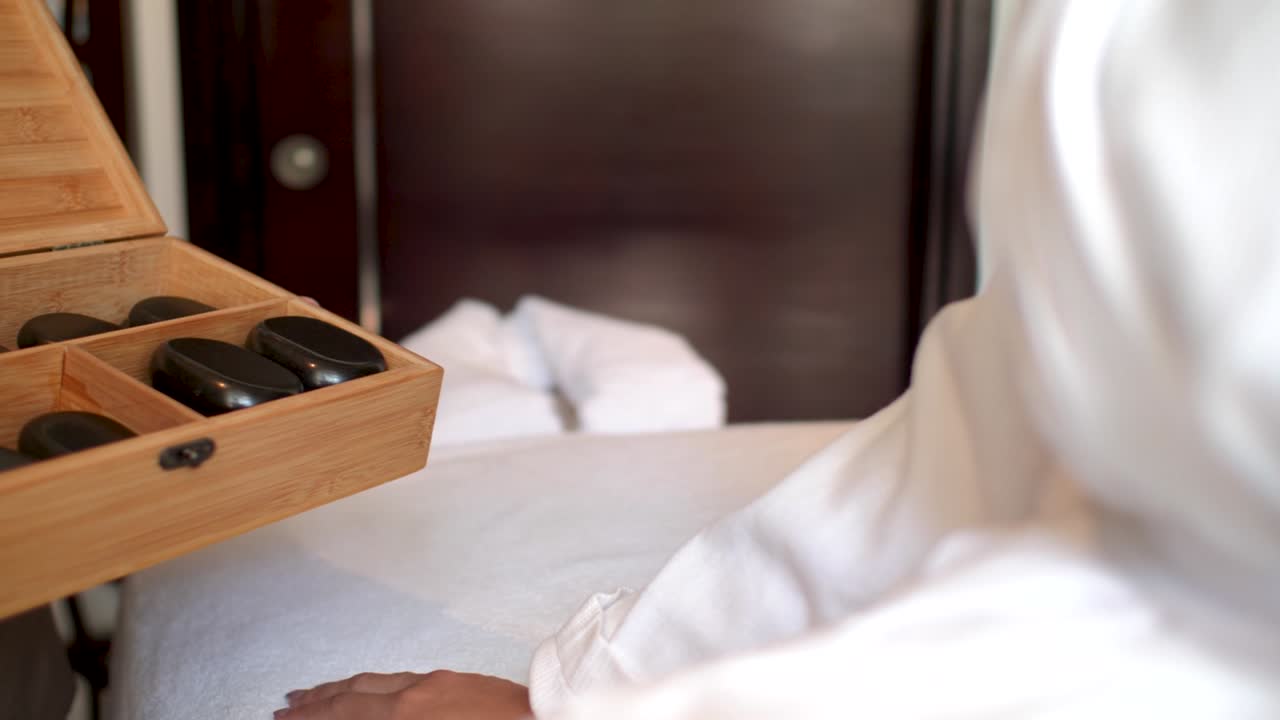 백인 아가씨에게 상자에 뜨거운 돌을 보여주는 안마사