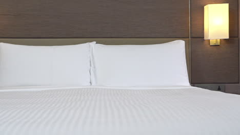 cacerola lenta a la izquierda en la cama hecha en la habitación de hotel moderna