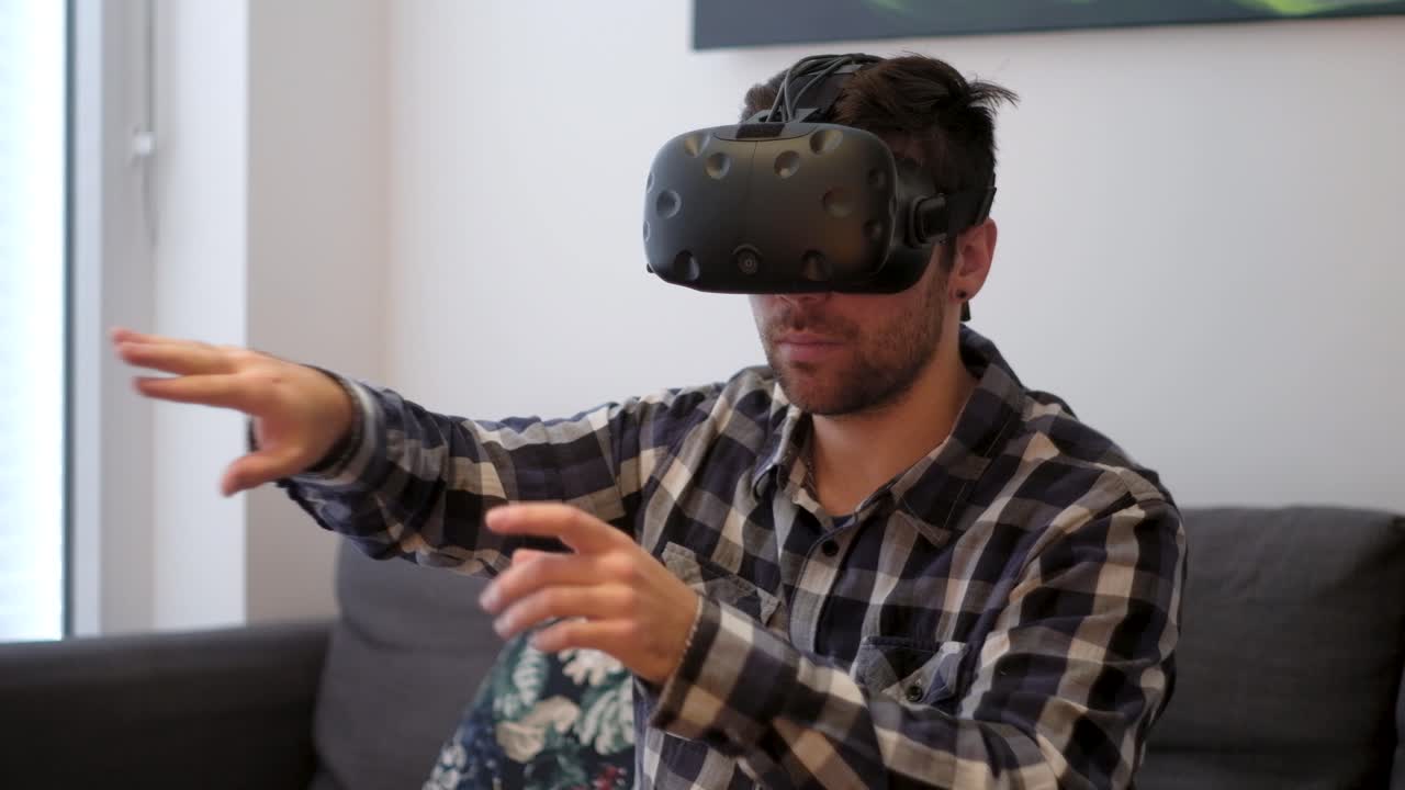 una toma mediana de un joven blanco que usa la realidad virtual en casa en un sofá