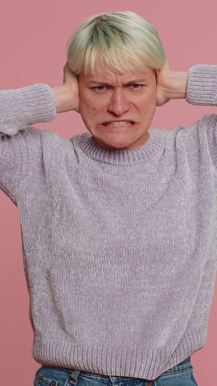 Ragazza irritata e irritata che copre le orecchie, che fa gesti, che non evita i consigli, che ignora il rumore, le voci forti.