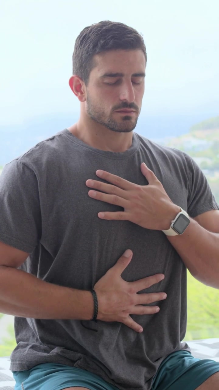 Vídeo vertical: Homem sentado pressionando as mãos no peito e na barriga, verificando a respiração na varanda, smartwatch