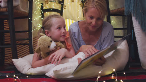 front view of caucasian woman reading a story to her daughter at home