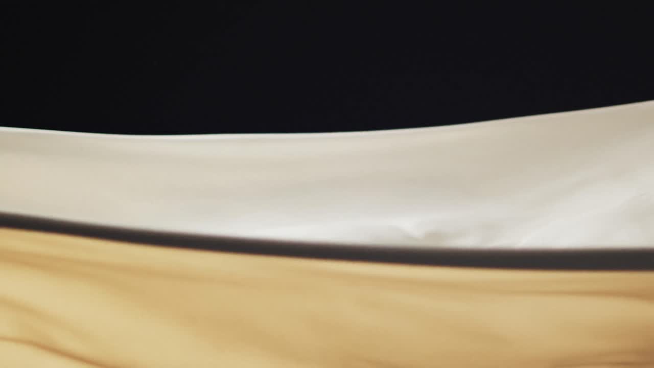 Animation of cream fabric blowing with copy space over black background