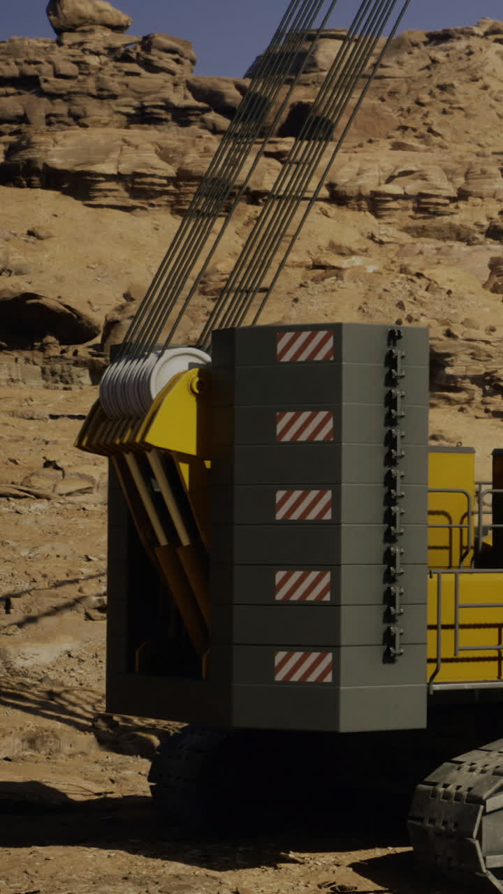 A large yellow machine works on uneven ground in a desert setting