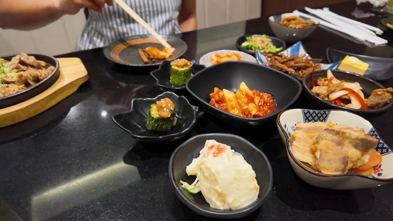 Jarak dekat seseorang menggunakan sumpit untuk makan berbagai hidangan kecil di restoran di Bangkok.