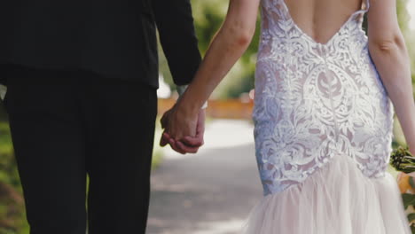 woman in lacy dress and man in suit walk along summer park