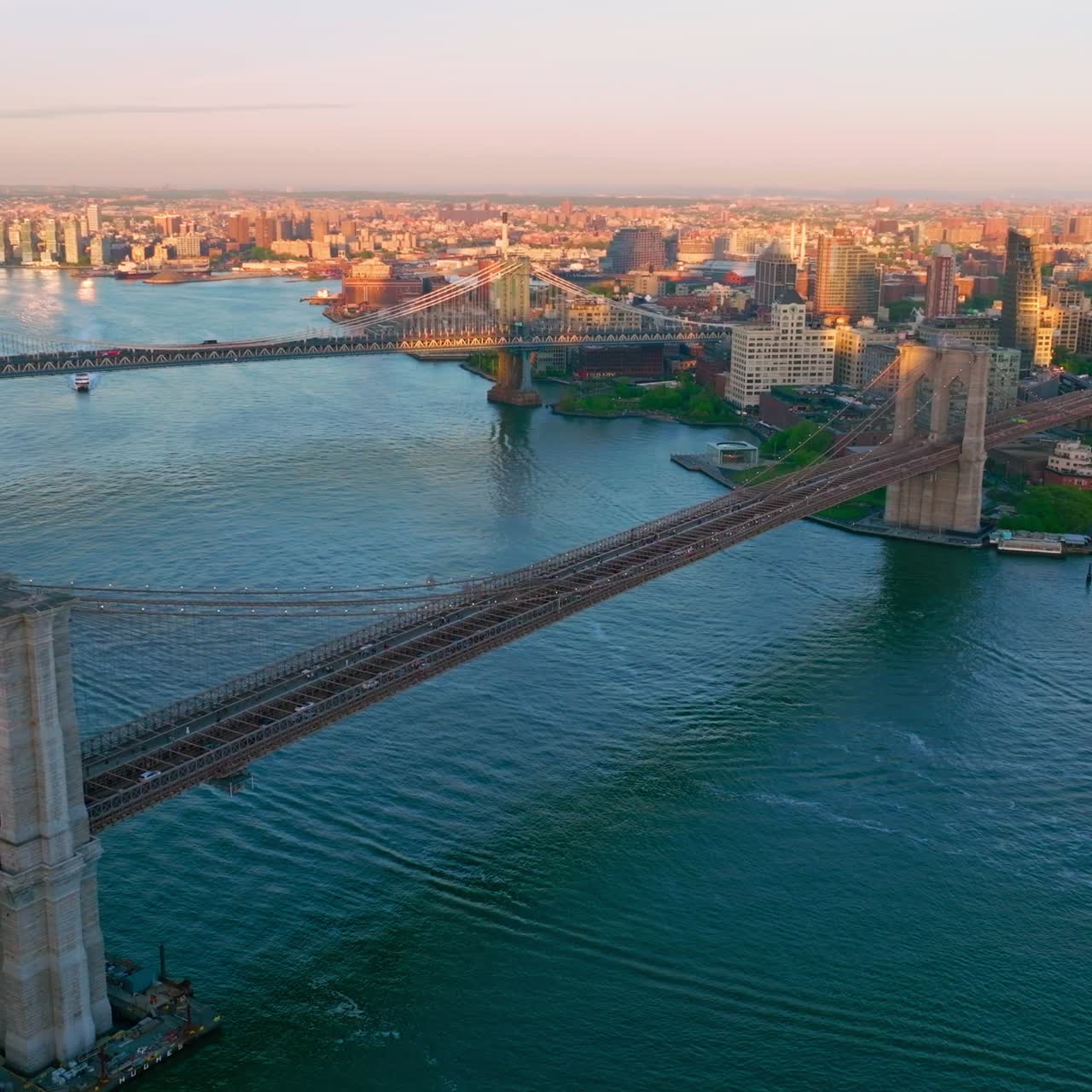 Two huge bridges crossing East river. Flying over the blue waters flowing through the fantastic New York city