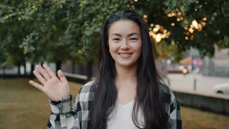 woman waving hello in a city park