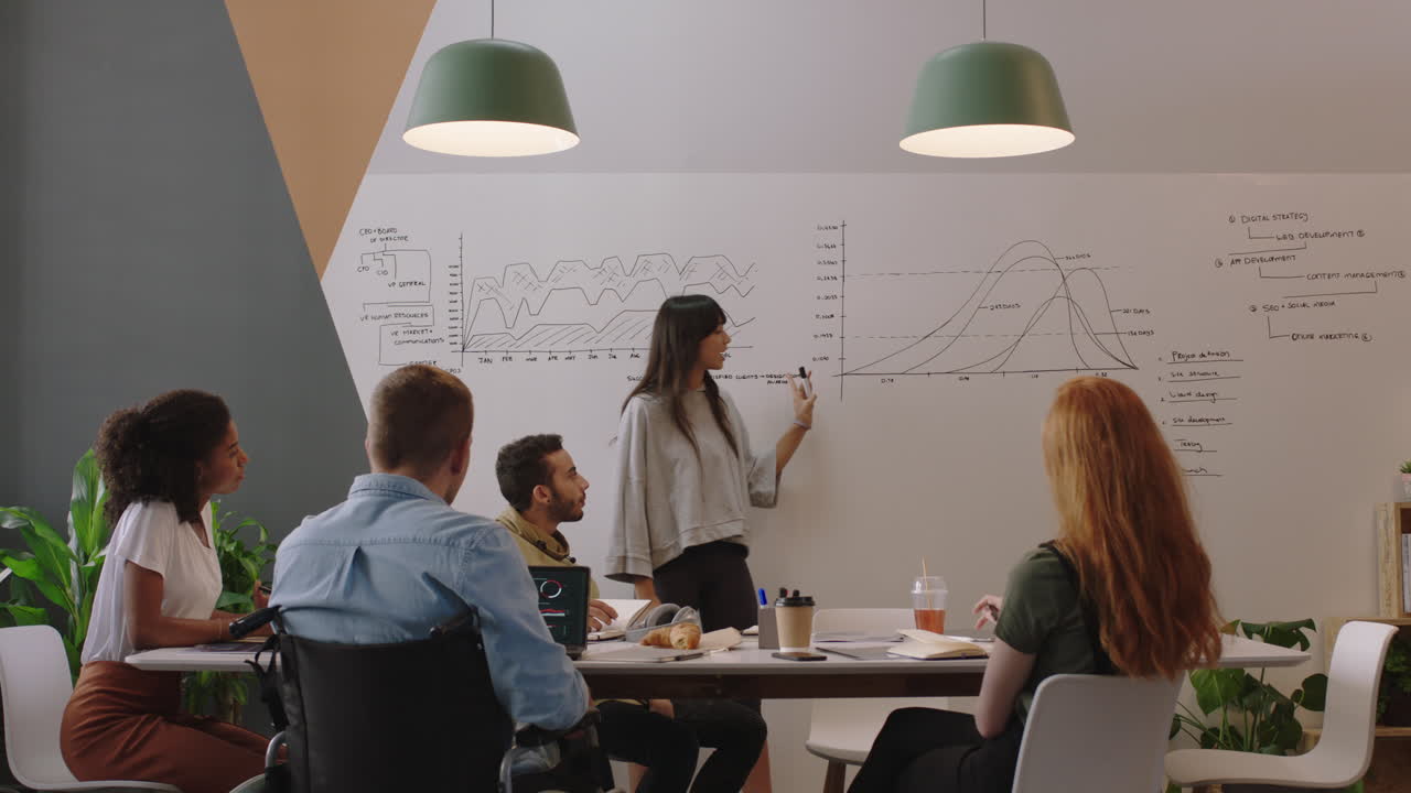 diverse business people meeting in boardroom brainstorming team leader woman presenting financial graph data showing colleagues presentation working together in disabled friendly office