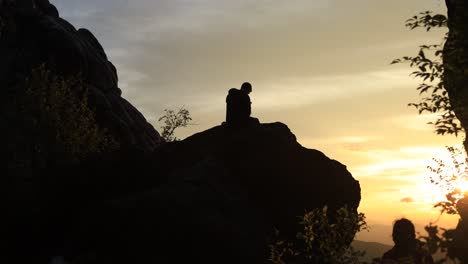 Un-Hombre-Se-Sienta-En-Silueta-Sobre-Una-Gran-Roca-En-El-Monolito-De-Roca-De-Dientes-De-Dragón-En-El-Sendero-De-Los-Apalaches-En-Virginia-Y-Observa-El-Amanecer