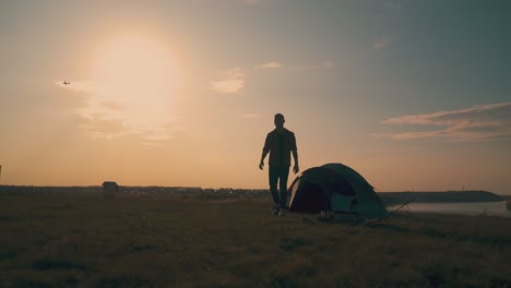 Silhouette-Eines-Mannes,-Der-Auf-Einem-Campingplatz-Auf-Einem-Hügel-Aus-Dem-Zelt-Geht