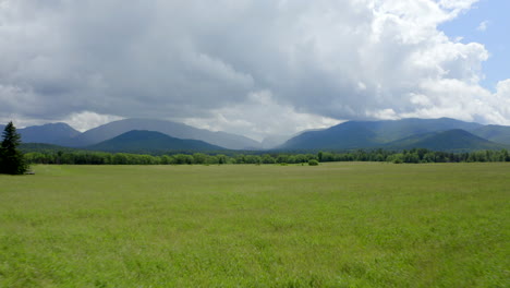 tiro aéreo de bajo vuelo acercándose a las exuberantes montañas verdes de adirondack con nubes de tormenta sobre su cabeza