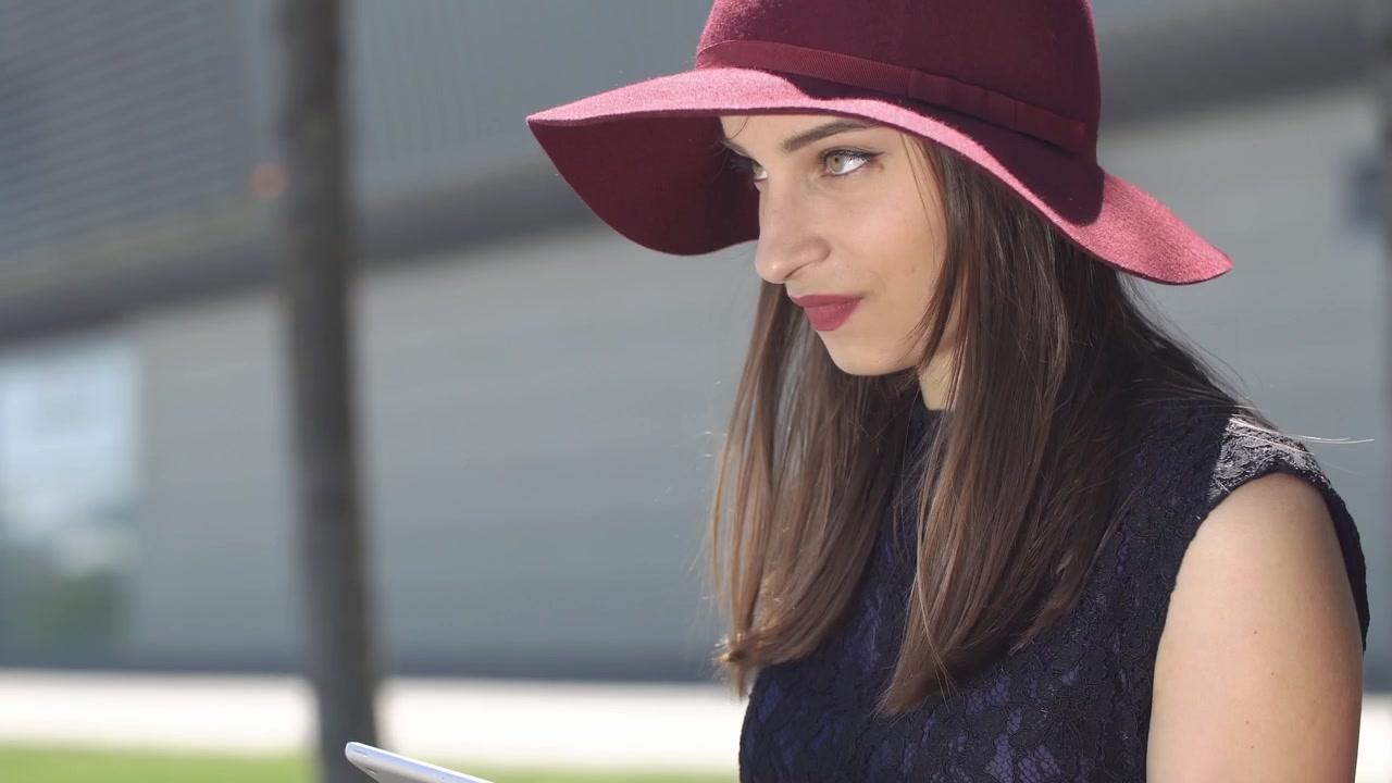 Donna elegante che sorride mentre usa un tablet all'aperto