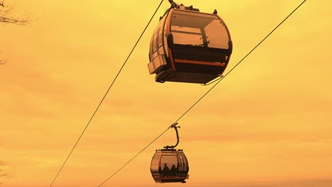 Kabinen-Der-Bergseilbahn,-Die-Mit-Einem-Orangefarbenen-Himmel,-Der-Wie-Mars-Aussieht,-Den-Berg-Hinauffahren