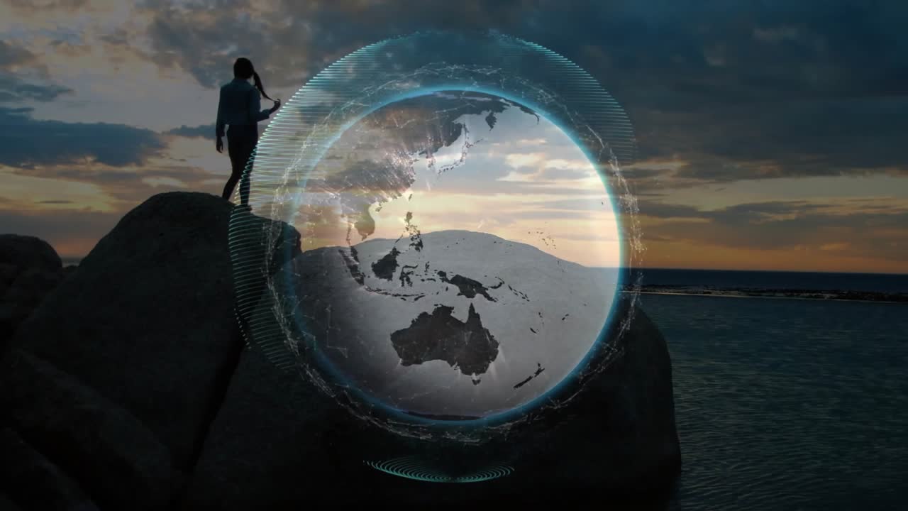 Donna in piedi su una roccia al tramonto che attiva un globo tecnologico che appare, ruota e registra