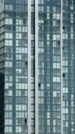 closeup of light passing over windows of skyscraper office blocks in london in vetical