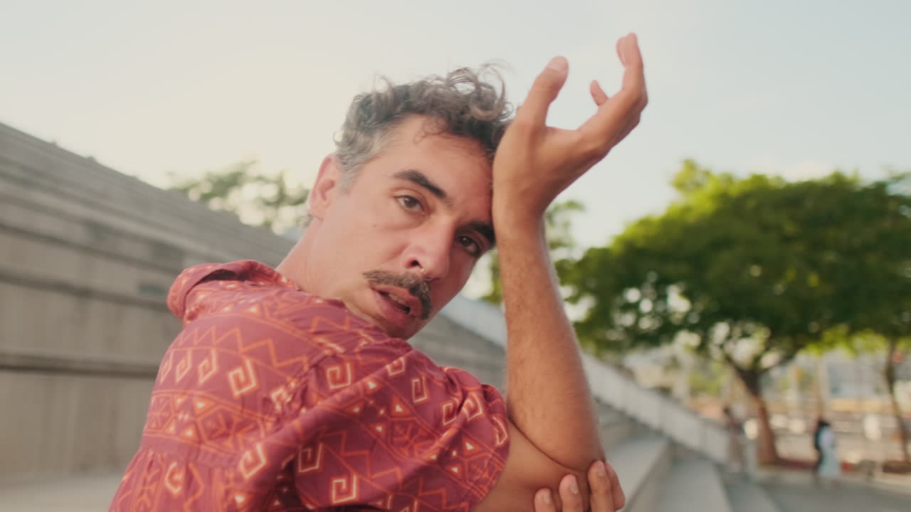 Hombre enérgico con bigote y aro en la nariz bailando al aire libre