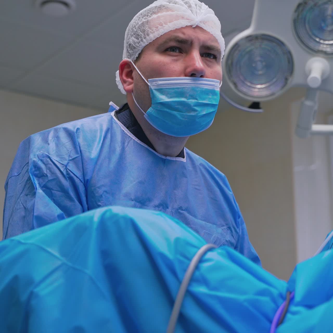Portrait of a surgeon in mask at work. Specialist looking seriously at something during the operation in clinic. Medicine concept.