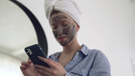 woman with facial mask using a smartphone