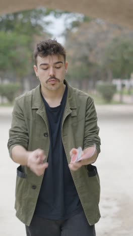 young man performing card magic tricks in a park