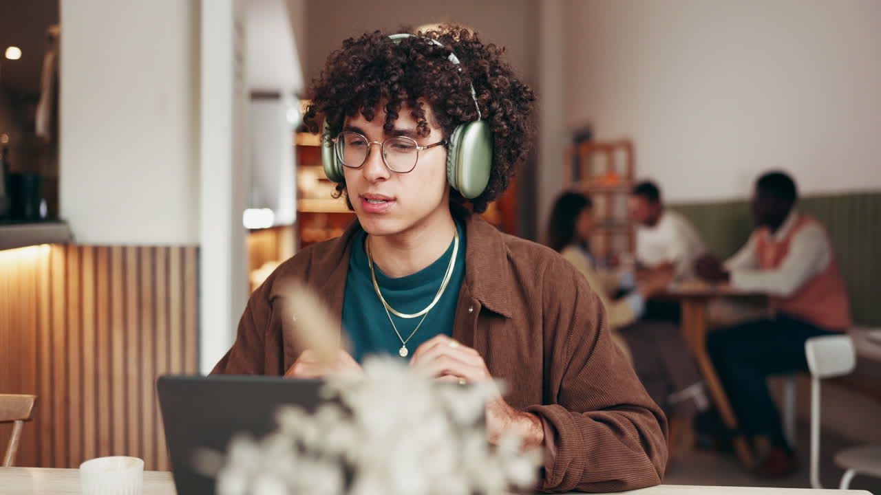 Man working on laptop with headphones in cafe