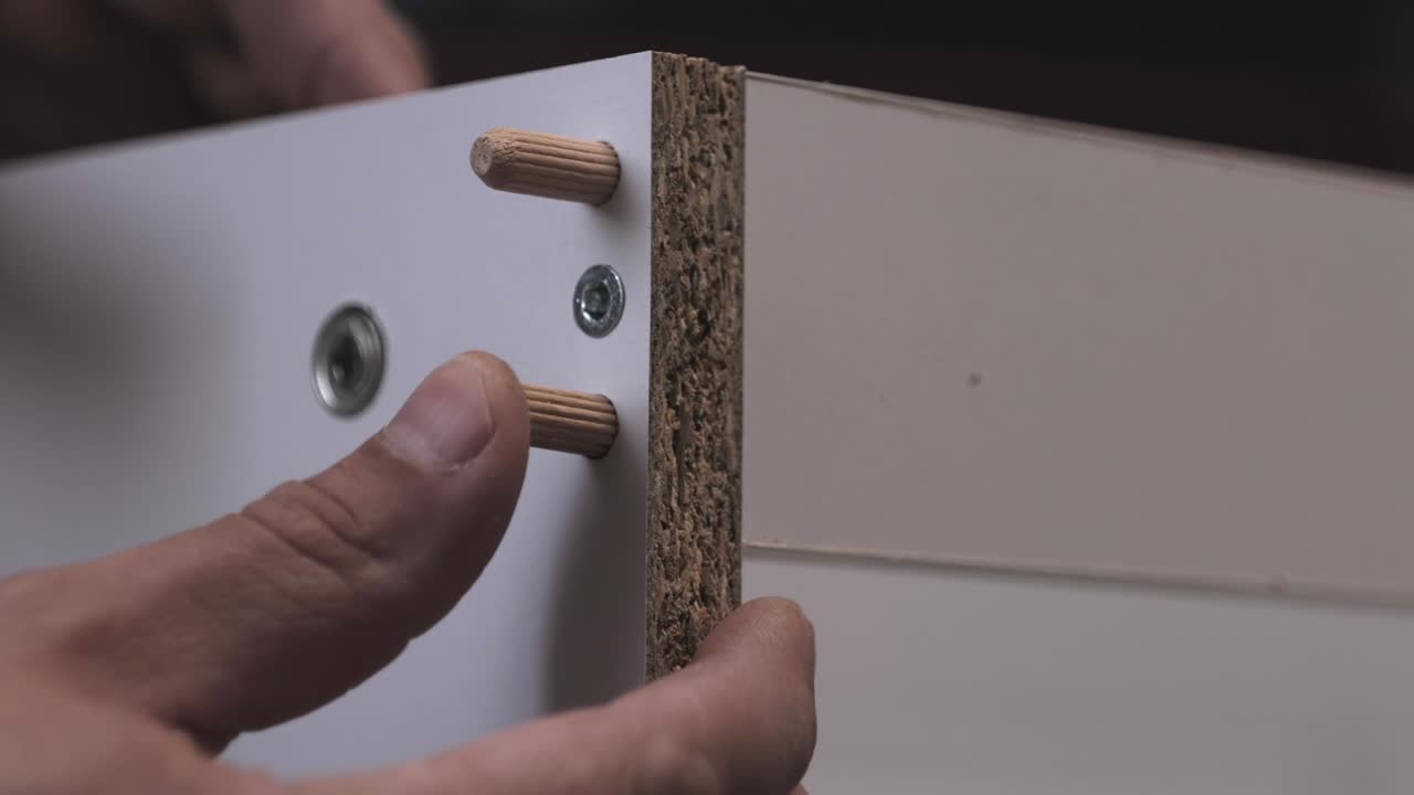 installation of wooden dowels in a hole in a chipboard. wood furniture assembly