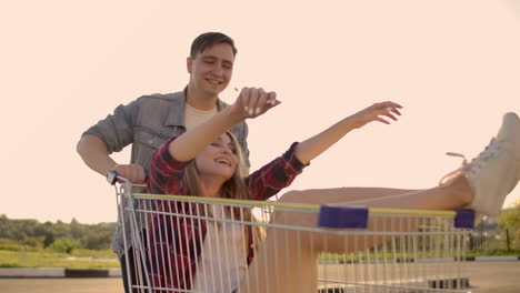 young friends having fun on shopping trolleys. multiethnic young people racing on shopping cart. slow motion