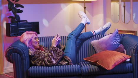 beautiful young caucasian woman in sunglasses using smartphone lying on sofa in vintage room at home