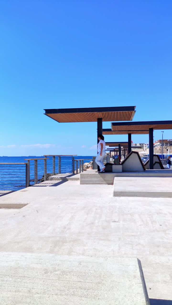 Turista in piedi sotto un moderno riparo in legno che guarda l'oceano