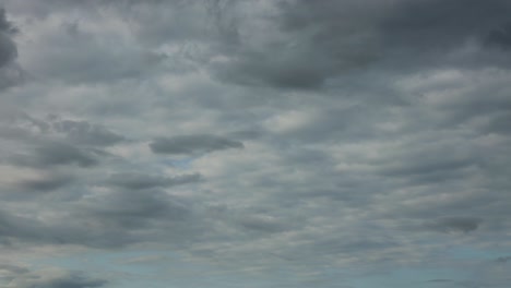 Dramatic-slow-cumulus-cloud-formations-forming-a-blanket-dissipating-and-revealing-blue-sky-in-the-background