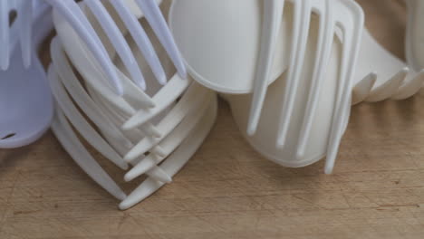 close up pan across a pile of single-use plastic utensils