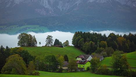 low clouds in a valley by an austrian village in autumn - time lapse