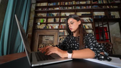 woman working on laptop in a cozy library setting