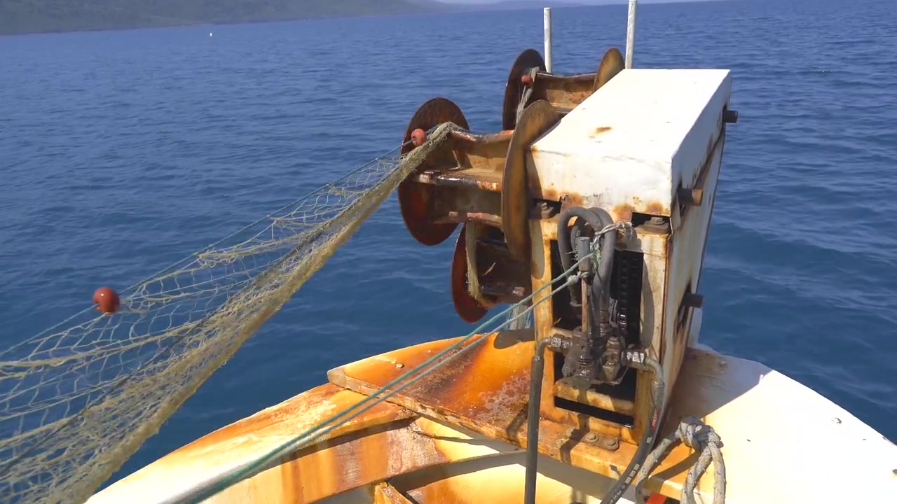 Rete da pesca recuperata da un verricello su una barca in mare