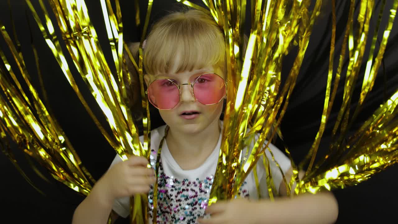 un niño feliz saltando, jugando, divirtiéndose en una cortina dorada de láminas brillantes.