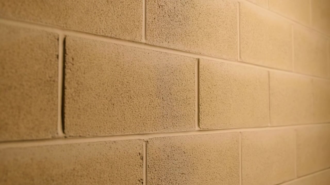 Tiled wall static, in indoor possibly bathroom or kitchen, with tiled wall, with ceramic tiles texture, from a side view slightly angled perspective, with beige, brown accents, and neutral mood.