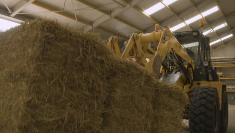 a large machine picks up a massive hay bale