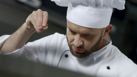 portrait of chef salting food at kitchen. chef cooking food in slow motion